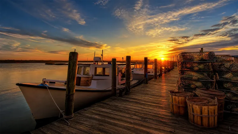 Chesapeake Bay workboats with low cabins tied up at a weathered wooden dock at sunrise, How to Get a Commercial Crab or Waterman License in Maryland